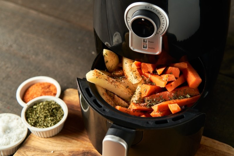 Cooking potatoes and carrot sticks with spices in an air fryer