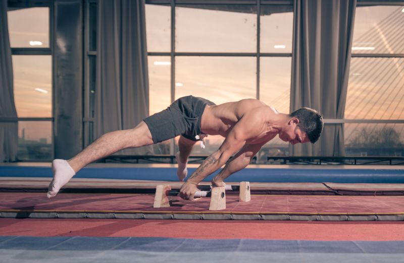 man wearing shorts no shirt working out exercising on bars calisthenics