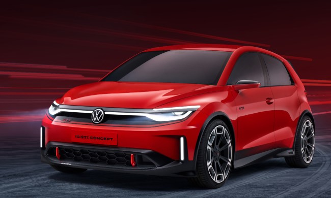 Volkswagen GTI EV concept in red left front three-quarter view on a loose gray gravel surface.